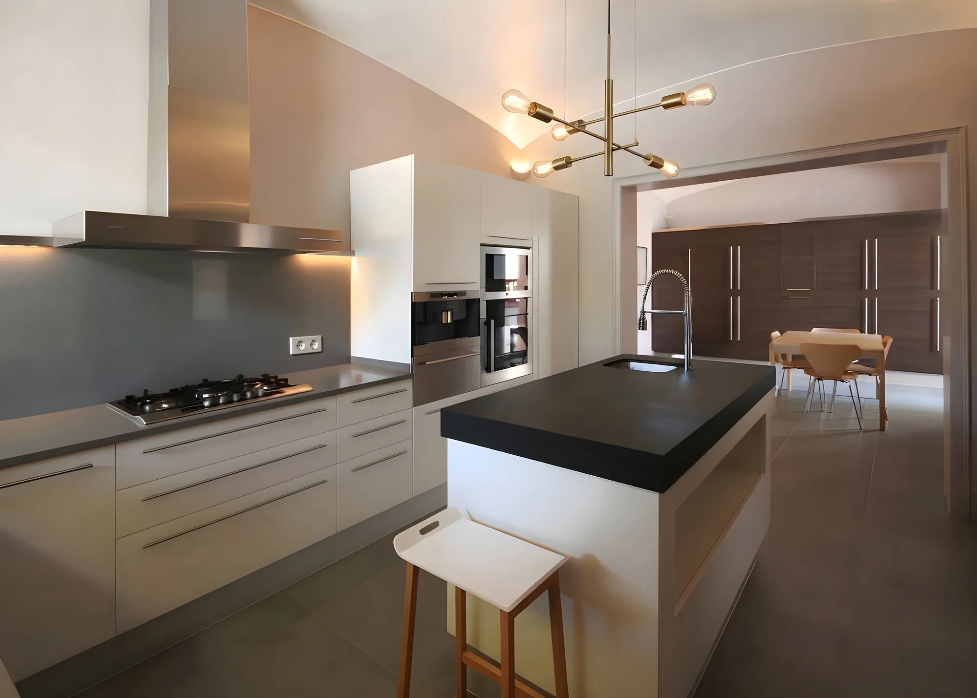 Cocina con isla negra y lámpara dorada en una vivienda reformada en Premià de Mar