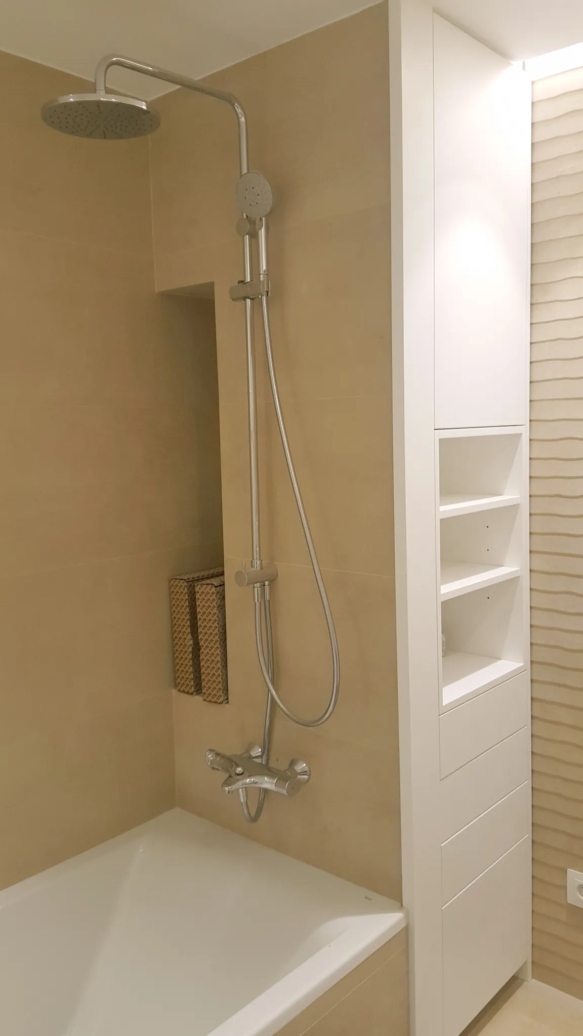 Baño con ducha, bañera y mueble columna blanco en una vivienda de Castelldefels