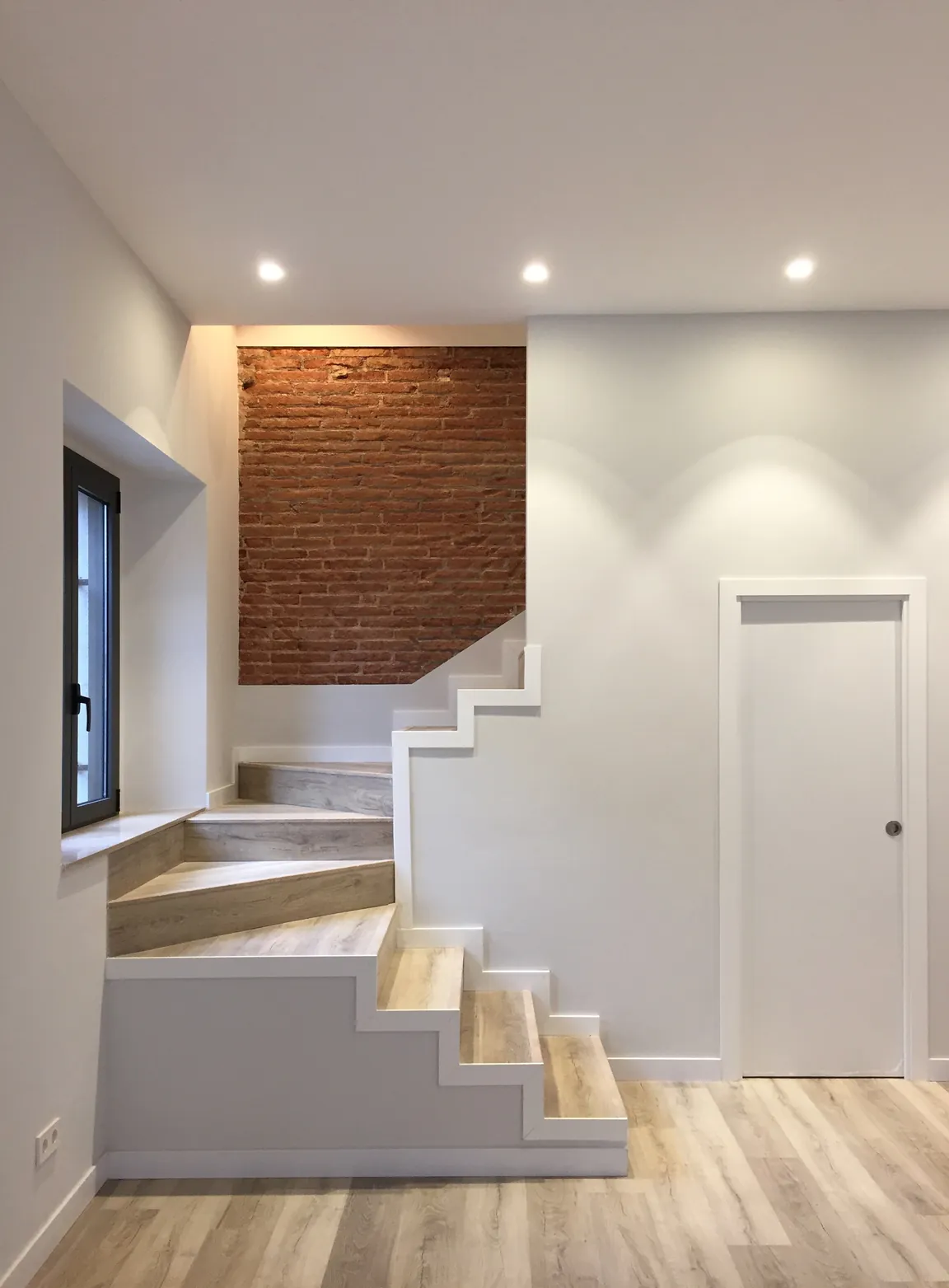Entrada con escalera y pared de ladrillo visto en Mataró
