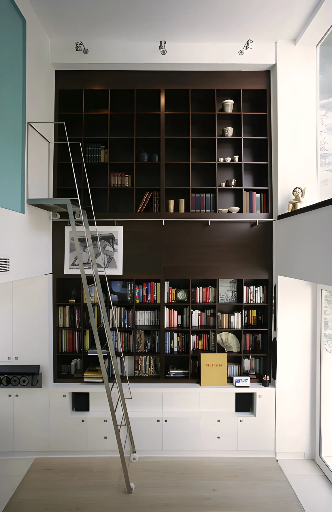 Librería de doble altura en madera oscura con escalera metálica en una vivienda de Pedralbes